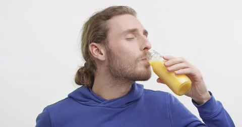 Attractive Smiling Guy Drinking orange Juice from Bottle Looking at the Camera Video stock 151519506