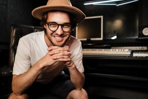 Attractive smiling guy joyfully posingon camera in sound recording studio. Young Stock Photos