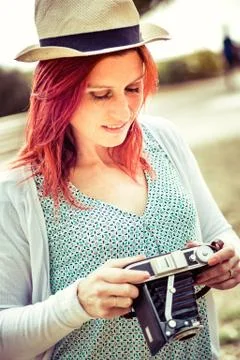 Attractive smiling redhead about to settle her old camera. vintage treatment Stock Photos