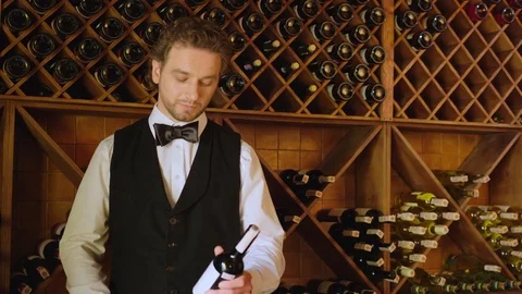 Attractive sommelier reading stock of wine on the wood background with wine Stock Footage