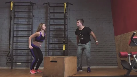 Attractive sports people are doing box jumps while working out in gym Stock Footage