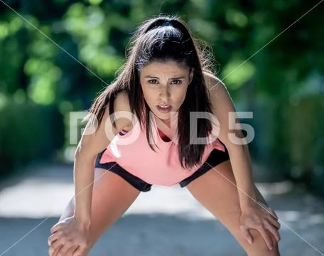 Attractive sports woman runner taking a break feeling tired afte Stock Photos