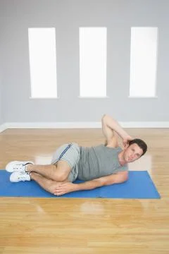 Attractive sporty man doing abdominal crunch looking at camera Stock Photos