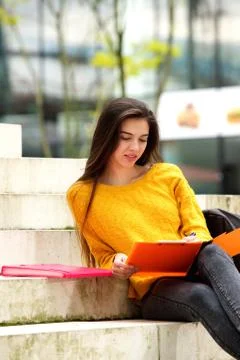 Attractive student sitting on steps studying Stock Photos