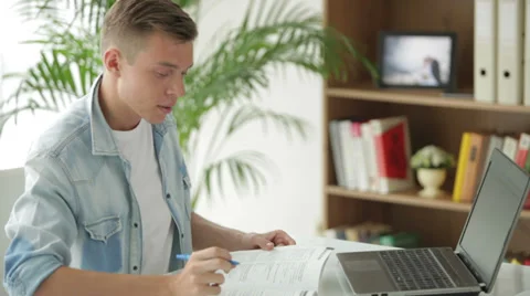 Attractive student sitting at table using laptop and writing in notebook Stock Footage 27692027