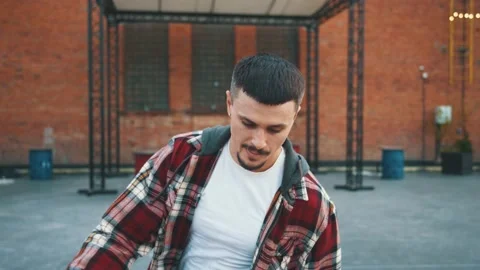 Attractive stylish b-boy demonstrating basic dance positions training skills on Stock Footage 138410599