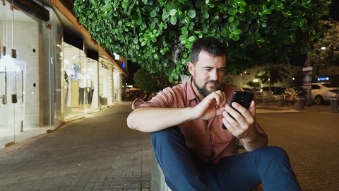 Attractive stylish young man scrolls his cellphone and smiles. Stock Footage 104565544