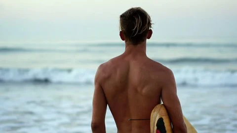 Attractive surfer man looking out towards ocean confident with surfboard. Stock Footage 108565235