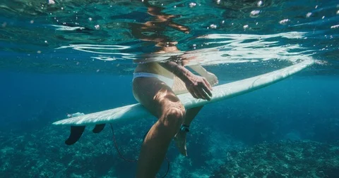Attractive surfer sitting on her surfboard Stock Footage 107972389