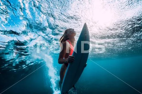 Attractive surfer woman dive underwater with under ocean wave. Stock Photos