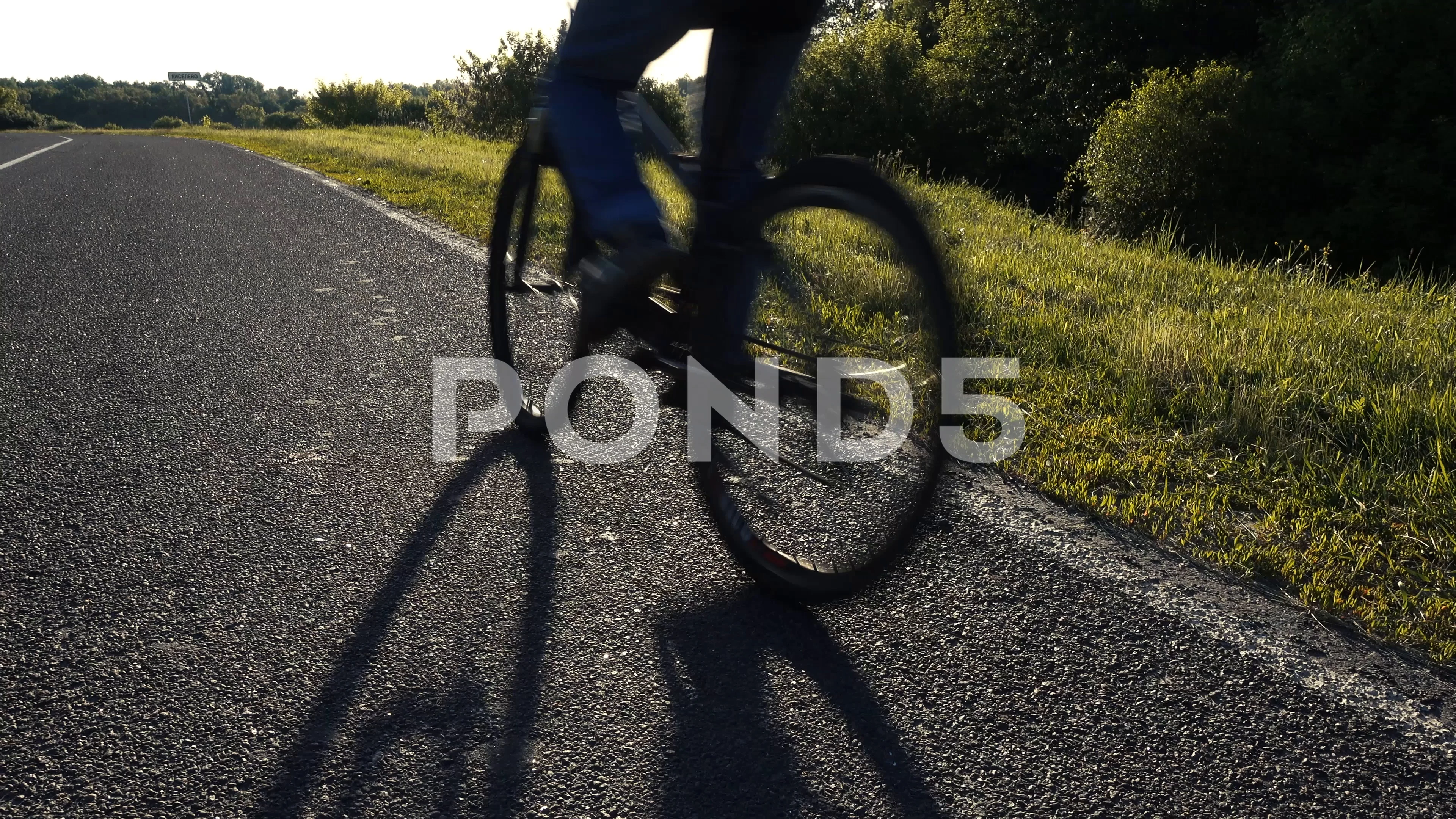 Attractive teen boy enjoying summer holidays and riding bicycle on park road