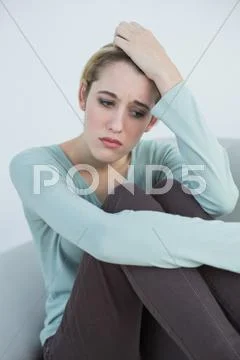 Attractive thoughtful woman sitting on couch Stock Photos