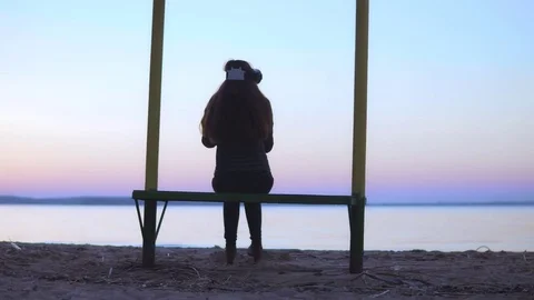 Attractive white woman is using virtual reality glasses by the lake at sunset Stock Footage 74738872