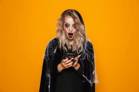 Attractive wizard woman wearing black costume and halloween makeup holding mo Stock Photos