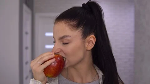 Attractive woman biting big red apple, looking at camera Stock Footage