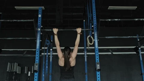 Attractive woman doing pull ups exercise. Wide angle of sporty woman in gym Stock Footage 112300452