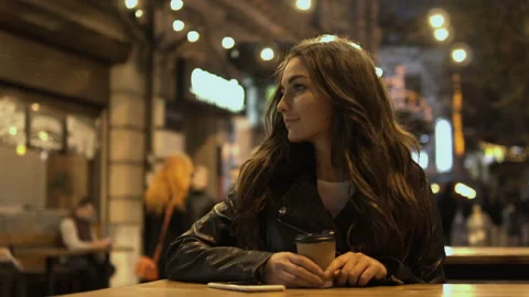 Attractive woman drinking coffee using a mobile phone while walking through the Stock Footage 98033093