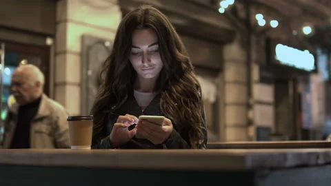 Attractive woman drinking coffee using a mobile phone while walking through the Stock Footage 98040575