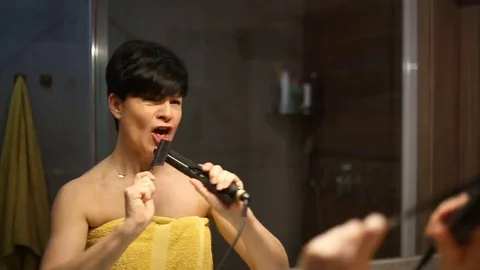 Attractive woman having fun while singing to the mirror in the bathroom Stock Footage 73752942