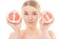 The attractive woman holding a grapefruit on the white background Photo