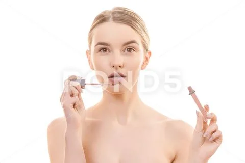 The attractive woman holding a lip gloss on the white background Stock Photos