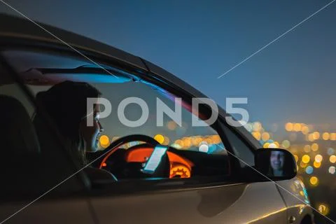 The attractive woman phone in the car on the background of the city. night ti Stock Photos