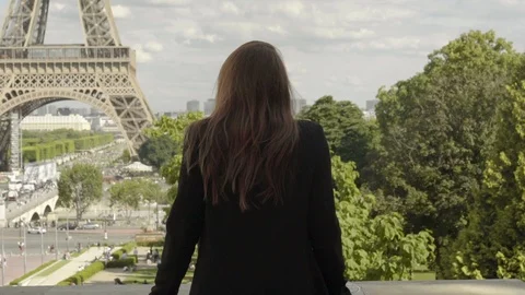 Attractive woman posing at the Eiffel Tower in Paris after work, with a black Vídeos de archivo 111924649