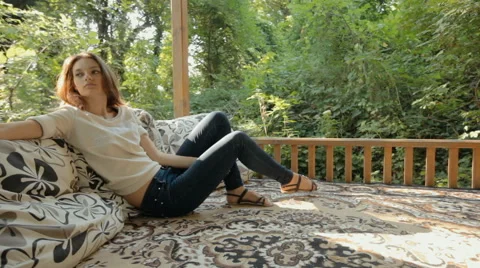 Attractive woman relaxing and sitting on pillows in the gazebo located in the Stock Footage 59321116