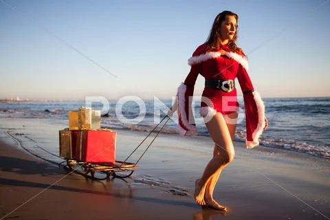 An attractive woman in Santa Claus costume pulling a sleigh Stock Photos