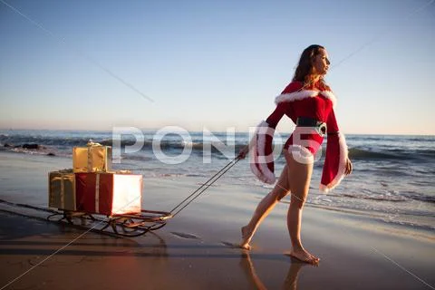An attractive woman in Santa Claus costume pulling a sleigh Stock Photos