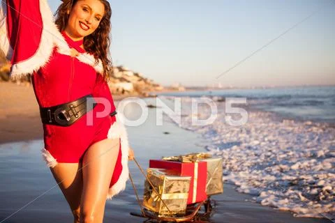 An attractive woman in Santa Claus costume pulling a sleigh Stock Photos