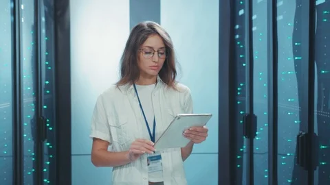 Attractive woman server specialist using tablet working in digital server farm Видео 119782898