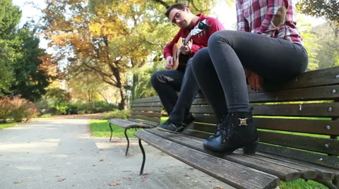 Attractive woman singing while man playing guitar in park Stock Footage 59557032