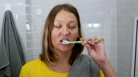 Attractive woman sings song and brushing teeth with toothbrush in bathroom Stock Footage