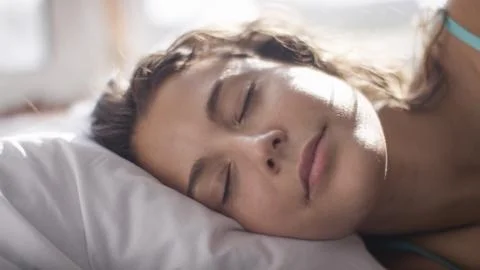 Attractive woman sleeping peacefully as morning light hits her face Stock Photos