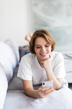 Attractive woman smiling as she reads an sms message on her mobile while rela Stock Photos