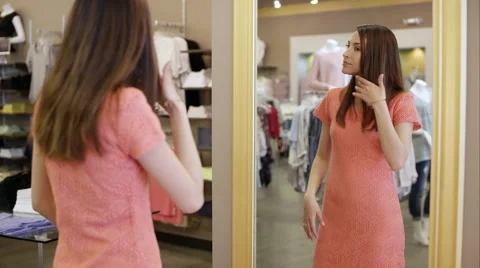 Attractive woman trying on dress and looking in mirror Stock Footage