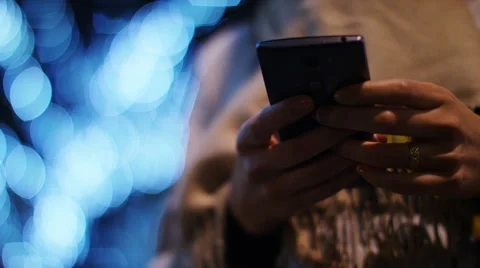 Attractive woman using her cell phone at night with blurred lights behind her Vidéo 58594864