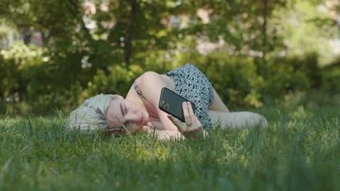 Attractive Woman Using Phone While Laying in Nature Vidéo 154390474