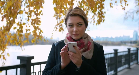 Attractive woman using smartphone on the background yellow leafs 库存影片 127640673