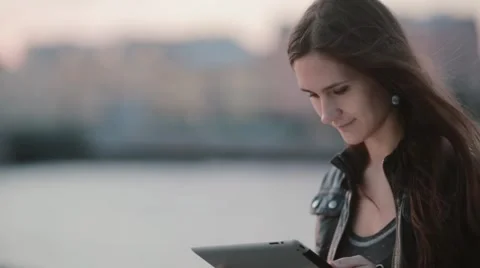 Attractive woman using a tablet. Pretty girl smiles looking at her tablet. Wind Stock Footage 67949463
