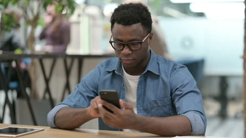 Attractive Young African Man using Smartphone in Modern Office Stock Footage 151416947