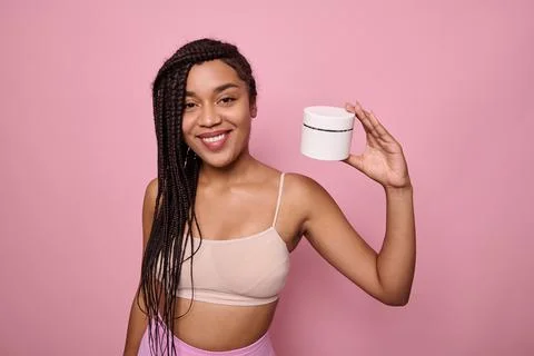 Attractive young African woman in beige underclothes smiles toothy smile hold Stock Photos