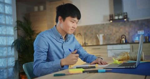 Attractive young Asian creative man writing notes on colorful stickers alone at Stock Footage 124326327