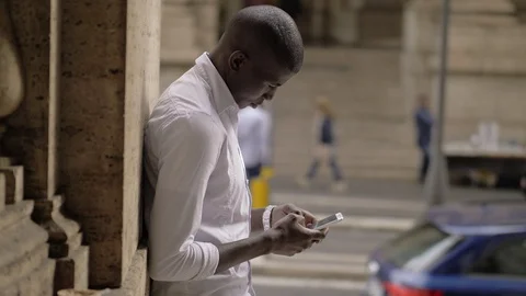 Attractive young black man typing on smartphone in the city Video stock 101827389
