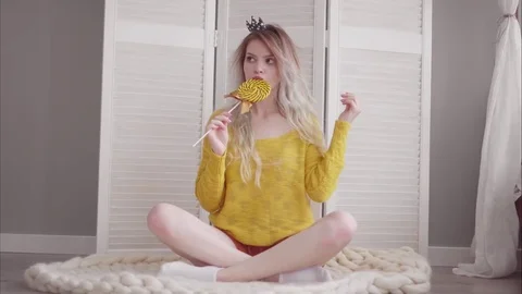 Attractive young blonde whith long hair sit on a floor in her bedroom eat Stock Footage 80183487
