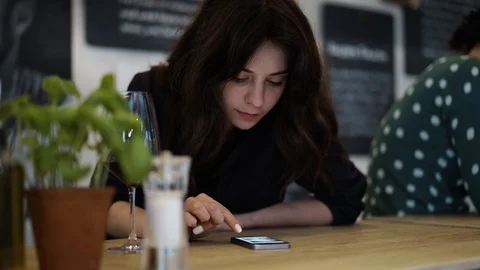 Attractive young brunette using her smartphone in a German cafe Video stock 88260112