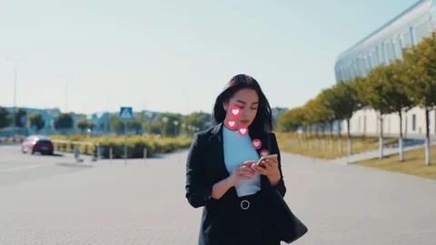 Attractive young business lady using a smartphone receiving love signs from Stock Footage 121471609