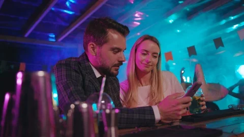 Attractive young couple looking through funny photographs on smartphone sitting Stock Footage 115361306