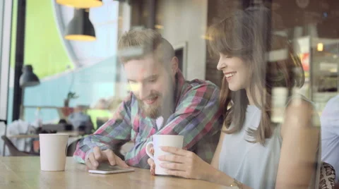 Attractive young couple using smartphone at cafe 動画素材 64648585